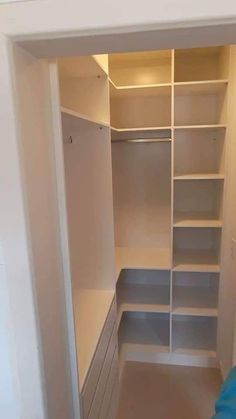 an empty walk in closet with white shelves