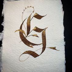 a piece of paper that has some type of calligraphy written in gold on it