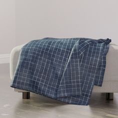 a blue and white plaid blanket sitting on top of a wooden floor next to a couch