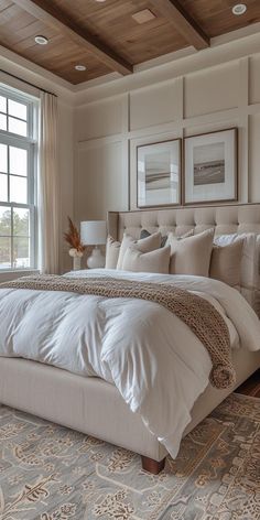 a large white bed sitting in a bedroom next to a window with lots of windows