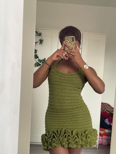 a woman taking a selfie with her cell phone in front of her face while wearing a green crocheted dress