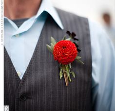 a man wearing a vest with a red flower on his lapel