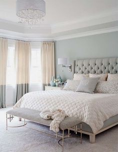 a bedroom with a bed, chandelier and curtains