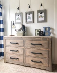 a dresser with drawers and pictures hanging on the wall