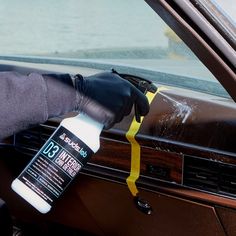 a person is cleaning the inside of a car with a bottle of deodorant