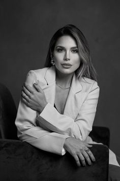 a black and white photo of a woman with her arms crossed, leaning on a chair