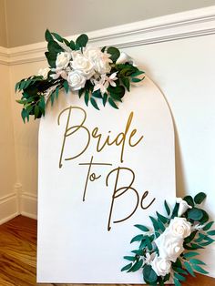 a sign that says bride to be with flowers on it and greenery around the edge