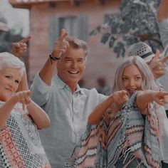 an older man and two younger women giving the peace sign