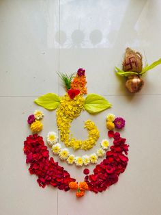 flowers and leaves arranged in the shape of a smiley face on a white tile floor