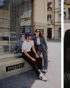 two people sitting in front of a store window and one person leaning against the wall