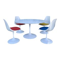 three chairs and a table with four different colors on the top one is red, yellow, blue, and white