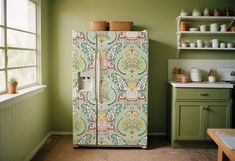 a green and white refrigerator in a kitchen next to a window with potted plants on it