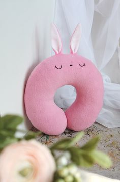 a pink donut with bunny ears sitting on top of a table next to flowers