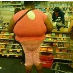 a woman standing in front of a grocery store filled with food and people looking at items