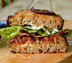 a sandwich with meat and lettuce on it sitting on a wooden cutting board