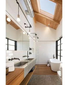 a large bathroom with a skylight above the bathtub and wooden flooring is shown