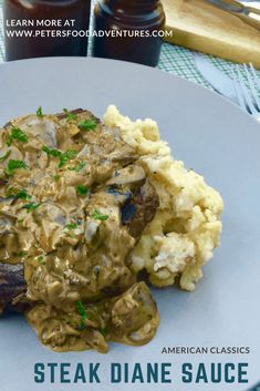 a white plate topped with meat covered in gravy next to mashed potatoes