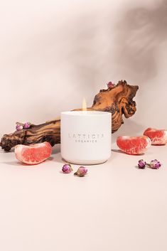 a candle surrounded by grapefruits on a white surface