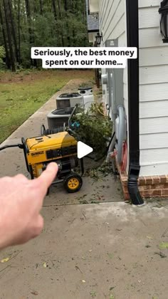 a person pointing at a small yellow machine on the side of a house that has been knocked over