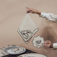 a woman holding up a piece of paper with drawings on it