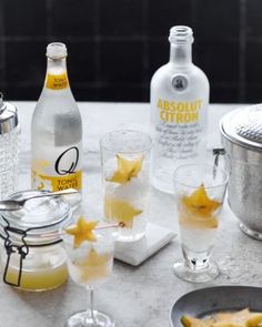 a table topped with bottles and glasses filled with drinks next to ice buckets on top of a counter