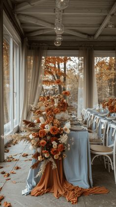 an outdoor dining area with blue and orange table cloths, white chairs, and flowers