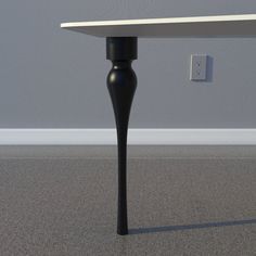 a black table with a white top on the floor next to a light switch and gray wall