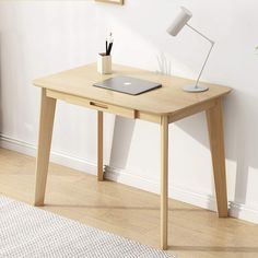 a laptop computer sitting on top of a wooden desk next to a lamp and potted plant