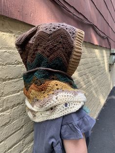 a person wearing a knitted hat on the side of a building next to a brick wall