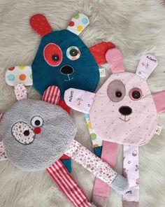 three stuffed animals laying on top of a white fur covered floor next to each other