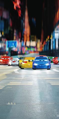 four cars are lined up on the street in front of some tall buildings at night