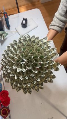 a person is making money out of rolled up bills on top of a white table