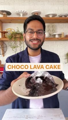 a man holding a plate with a chocolate lava cake on it in front of him