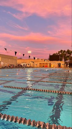 an empty swimming pool with no people in it at sunset or sunrise, and several kites flying overhead