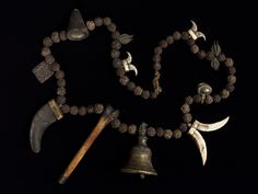 an assortment of ancient items displayed on a beaded necklace with bells and hammers