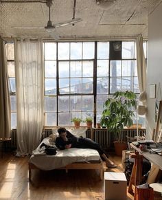 a person laying on top of a bed in a room filled with windows and furniture