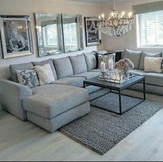 a living room filled with lots of furniture next to a chandelier and windows