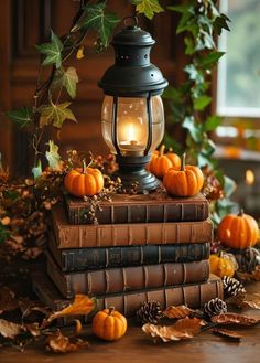 an old fashioned lantern is sitting on top of some books with pumpkins and leaves around it