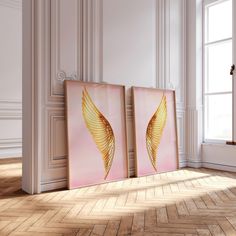 two paintings on the wall in an empty room with wood flooring and white walls