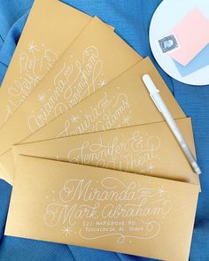 four envelopes with calligraphy on them next to a pen