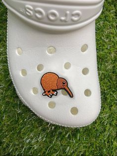 a white shoe with an orange kiwi sticker on it's soles