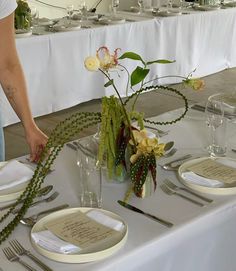 a table is set with place settings and flowers in vases on the tablescloth