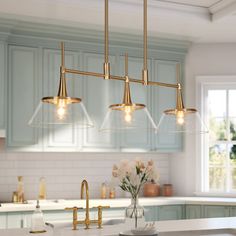 a kitchen with blue cabinets and white counter tops, gold fixtures and hanging lights over the island