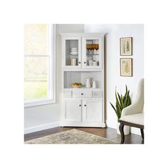 a white bookcase with glass doors and drawers in a room next to a window