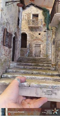 someone is holding their hand up to the stairs in front of an old stone building