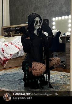 a person in a ghost costume taking a selfie with their cell phone while sitting on the floor