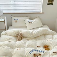 a bed with white sheets and teddy bears on it