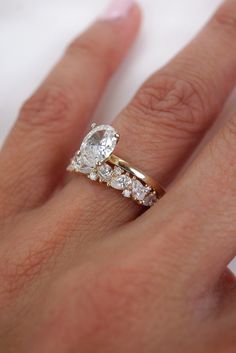 a woman's hand with a diamond ring on top of her finger and the other hand holding an engagement ring