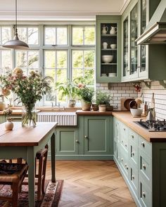 a kitchen filled with lots of green cupboards and counter top next to a window