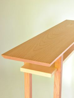 a close up of a wooden table with a white wall in the backgroud